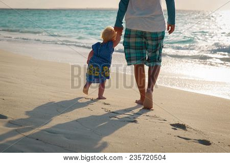 Silhouette Of Father And Little Daughter Walk At Sunset Beach