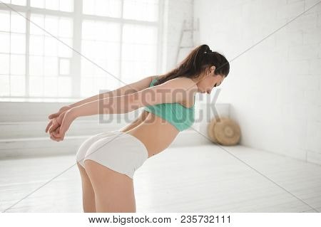 Young Sporty Woman Doing Streching Exercises In Bright Interior. Correct Posture. Perfect Rear. Prot