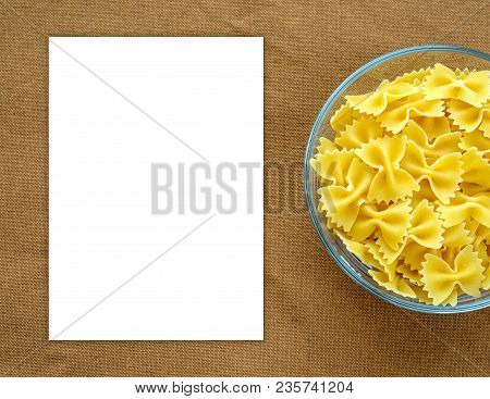 Farfalle Raw Pasta In A Glass Cup On A Brown Suburban Background Texture With A Side. Close-up With 
