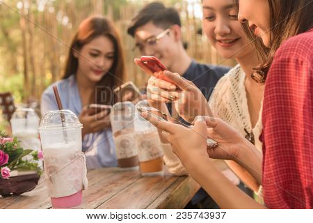 Group Of Teenager Adding Friend Play Social Media With Smartphone Together In Coffee Shop