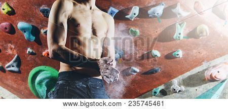 Man Climber Preparing To Climb Indoors In Bouldering Gym With Dramatic Light. Man Using Chalk. Hands