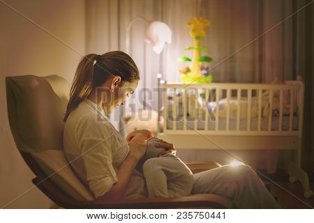 Young Beautiful Mother, Breastfeeding Her Newborn Baby Boy At Night, Dim Light