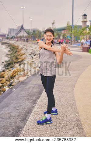 Sports Concept. Beautiful Girl Is Exercising On The Beach With Warm Up. Beautiful Girl Is Happy To E