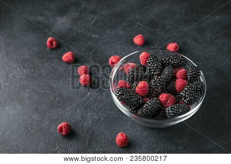 Glass Plate With Ripe Red Blackberries And Raspberries On A Black Surface. Macro Photo Of Ripe Black