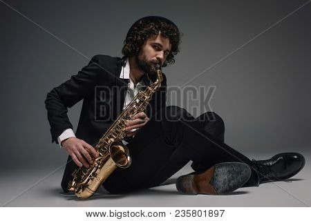 Bearded Jazzman Playing Saxophone While Sitting On Floor
