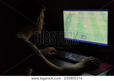 Man In Headphones Playing Computer Soccer Game At Night.