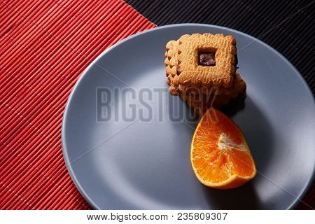 Chocolate Chip Cookies And Piece Of Orange On Plate And On Red And Black Background With Place For T