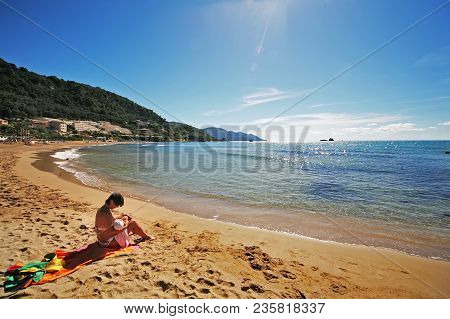Mother Breastfeeding A Child On The Beach, Kontogialos, Pelekas, Corfu, Greece