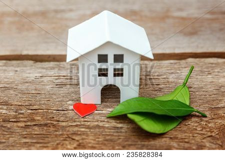 Miniature White Toy Model House With Green Leaves And Red Hearts On Wooden Backgdrop. Eco Village, A