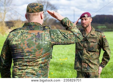 Two German Soldiers Salute Each Other On A Field