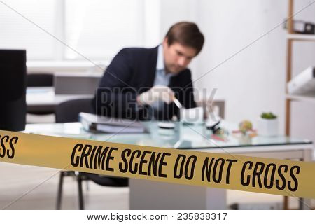 Forensic Expert Searching For Crime Evidence On Pencil Holder Behind Crime Scene Tape