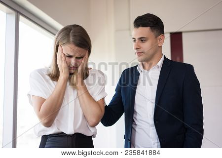 Businessman Consoling His Depressed Female Colleague. Serious Young Caucasian Businessman Patting St