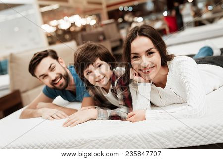 Lovely Bearded Man, Together With His Beautiful Wife And Son, Relaxes On The Mattress In The Store. 
