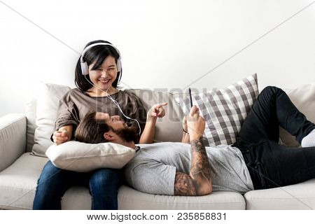 Interracial couple sharing music at home love, leisure and music concept