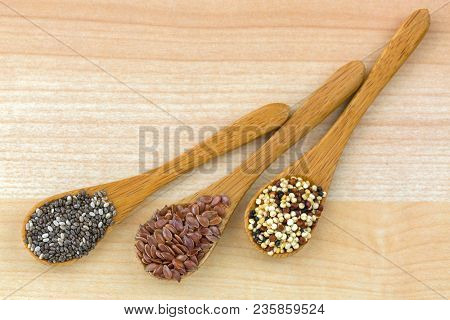 Dried Chia seed, Linseed flaxseed, Quinoa seed tri-color blend on wooden spoon, wood background