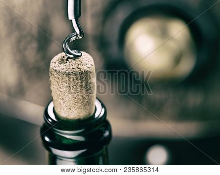 Opening wine bottle. Oak wine keg at the background.