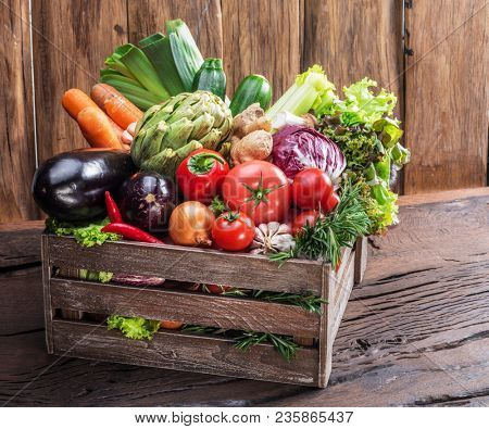 Fresh multi-colored vegetables in wooden crate. Organic food. Wooden background.