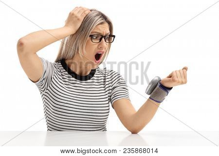 Shocked young woman sitting at a table and measuring her blood pressure isolated on white background