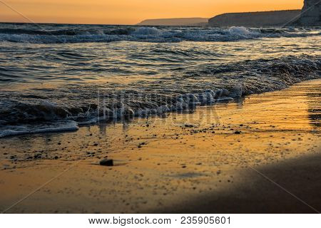 Waves Approaching Sandy Beach During Sunset