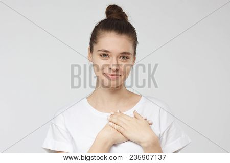 Portrait Of Smiling Positive Young Woman Keeps Hands On Chest, Expresses Sympathy. Kind Hearted Frie