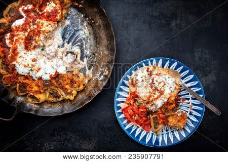 Traditional Turkey kolay yufka manti oven backed with lamb mincemeat as top view in a cast iron pan and a plate
