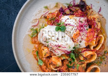 braised codfish filet and lettuce, herbs with calamarata noodles as top view on a plate