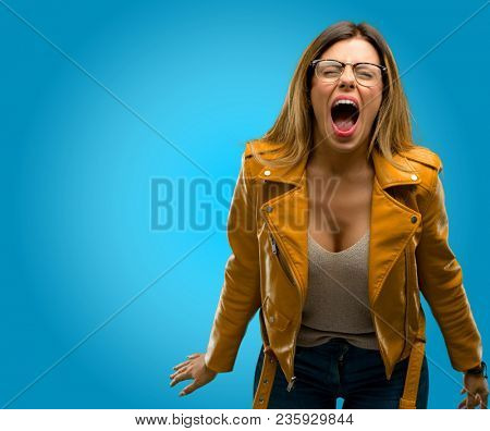 Beautiful young woman stressful, terrified in panic, shouting exasperated and frustrated. Unpleasant gesture. Annoying work drives me crazy, blue background