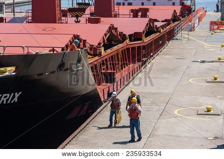 Sault Ste. Marie, Michigan/usa - June 26th, 2013: Group Of Workers Walking Beside Large Ship As It P