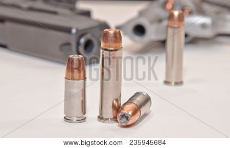 Four Bullets, Two 9mm And Two .357 Magnum With A Stainless .357 Revolver And A Black 9mm Pistol In T
