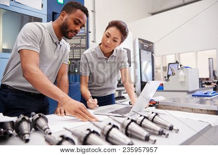 Two Engineers Using CAD Programming Software On Laptop
