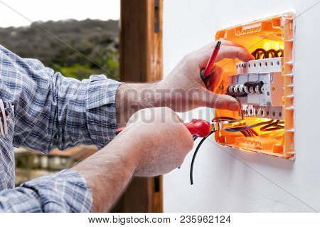 Electrician Technician Working On A Residential Electric Panel, Inserting The Wire With The Clamp