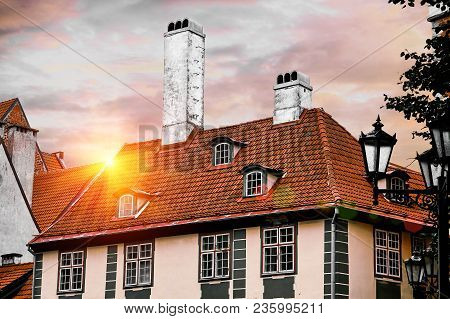 Roofs Of Old Houses In Skarnu Iela Street In Riga, Latvia Against Blue Sky With Awesome Lens Flares.