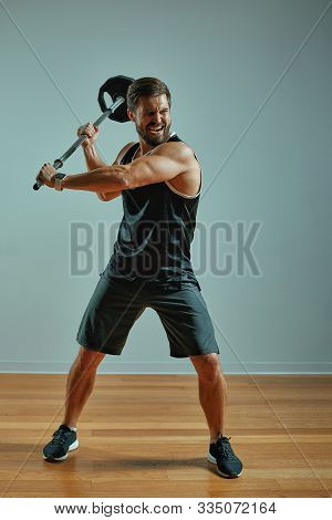 Man Sportsman Weightlifting. Muscular Man Attacks With Barbell