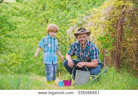 Planting Flowers. Growing Plants. Take Care Of Plants. Boy And Father In Nature With Watering Can. G