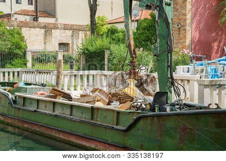 Morning In Venice. A Garbage Barge Equipped With A Garbage Compactor Picks Up Construction Waste Fro