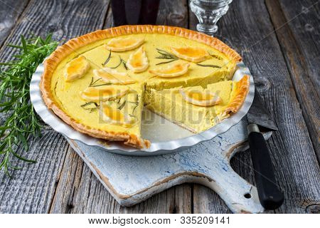 Traditional French Autumn pumpkin tarte offered as closeup in a backing form on an old wooden cutting board 