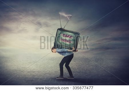 Bent Down Guy Carrying An Old Tv Box On His Back. Overloaded Man Bored Of Daily Fake News On Televis