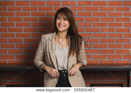 Image Of Smiling Long Brown Hair Asian Businesswoman Standing At Coffee Coner With Brown Bricks Wall
