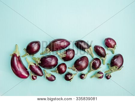 Eggplants Of Different Sizes On A Wooden Background With Mint Color. Top View, Flat Lay.
