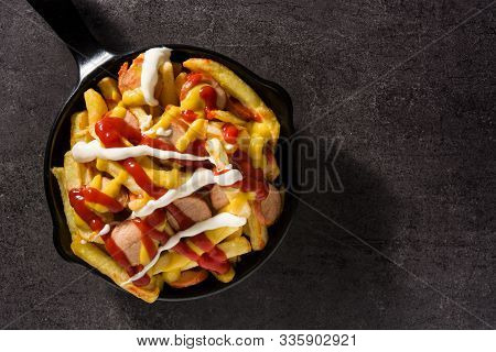 Typical Latin America Salchipapa. Sausages With Fries, Ketchup, Mustard And Mayo In Iron Pan And Bla