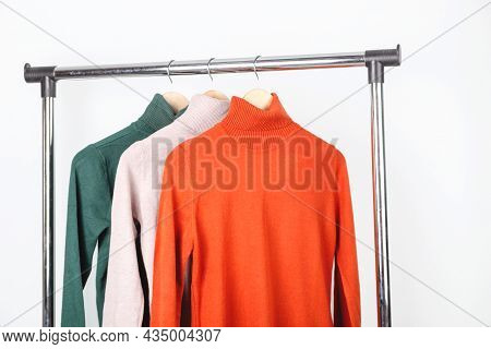 Blank Turtleneck Sweater Mockup On Clothes Hanger. Bright Orange Ocher Roll-neck With Beige And Gree