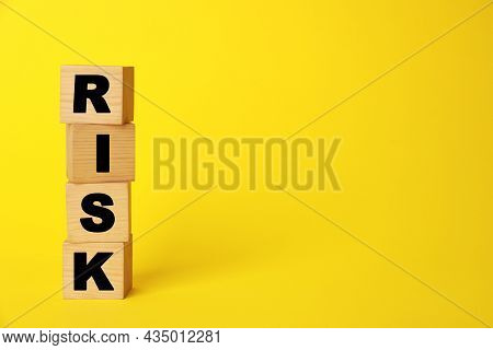 Word Risk Made Of Wooden Cubes On Yellow Background, Space For Text