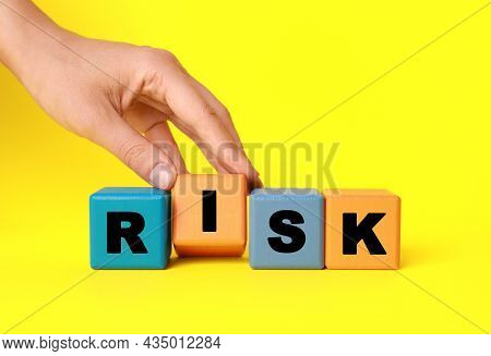 Woman Making Word Risk With Colorful Cubes On Yellow Background, Closeup