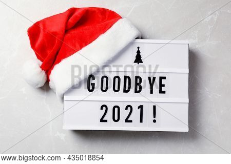 Lightbox With Text Bye Bye 2021! And Santa Hat On Light Grey Background, Flat Lay