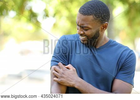 Black Man Scratching Itchy Arm Walking In A Park