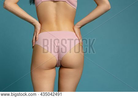 Back View Of Sportive Body, Bottocks Of Young Woman In Pink Panties Isolated On Blue Studio Backgrou