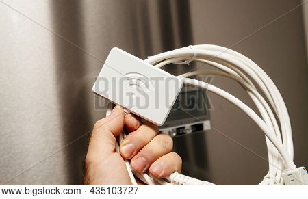 Male Hand Holding New Wifi Dongle For Modern Refrigerators With New Fridge In Background - Control W