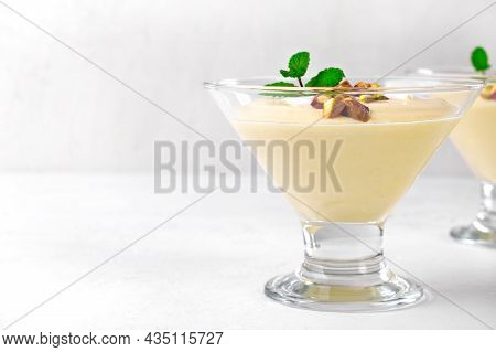 Mango Dessert With Yogurt Topped With Pistachio And Mint In Glass Bowl On The White Table. Copy Spac