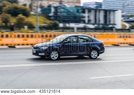 Blue Skoda Rapid Small Family Car Moving On City Road. Driver In 4-door Sedan Rushes For Job. Moscow