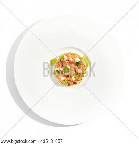 Restaurant dish - shrimp tartare with avocado, cream cheese, sweet chilli sauce on white plate. Ceviche with marinated prawn, avocado and spicy vegetables. Prawn tartare isolated on white background